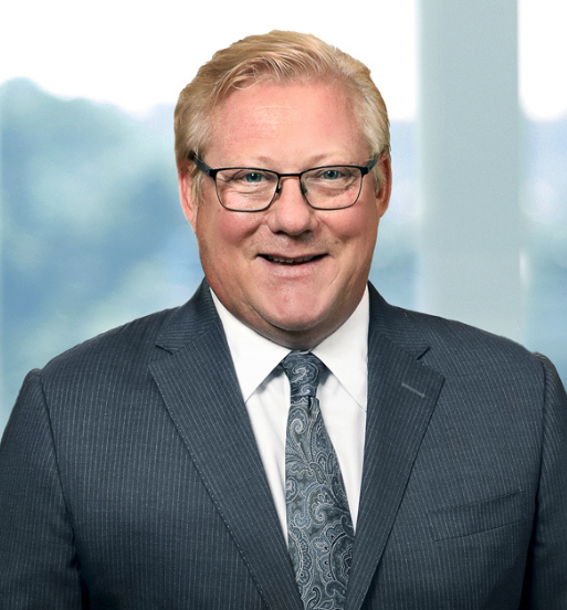 Fotografia de perfil do CEO da Viatris Scott Smith, junto a uma janela com o background desfocado.