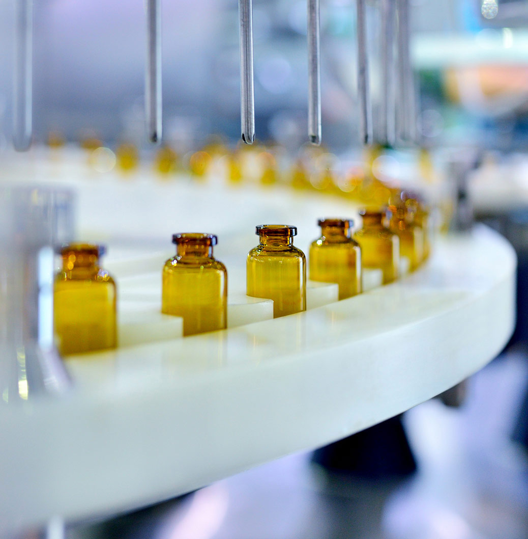 Linha de Produção de uma fabrica de produtos farmacêuticos. Vários frascos circulam numa estrutura rolante.